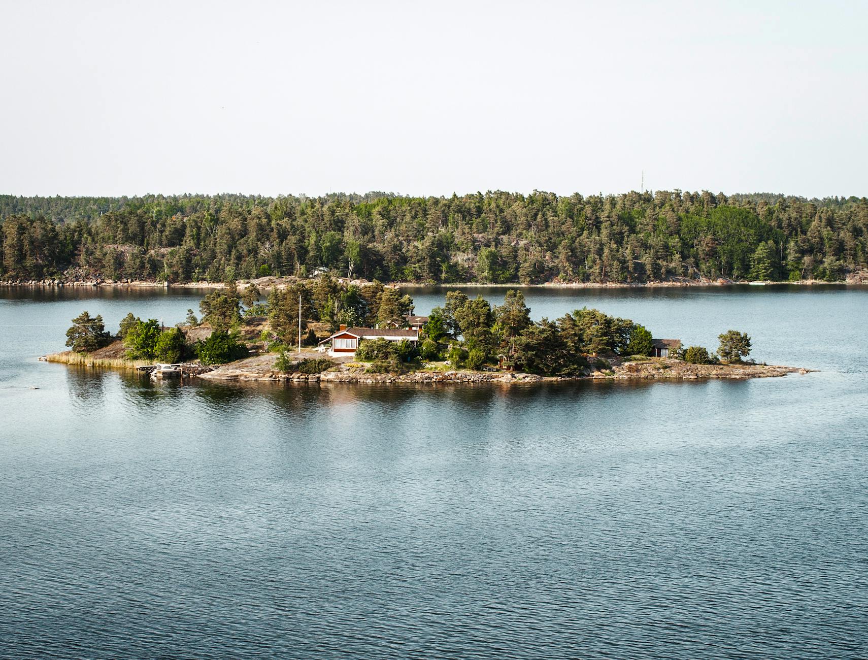 A red wooden cottage on a quiet Stockholm archipelago island surrounded by calm Baltic water